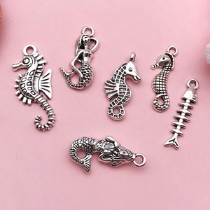 Detailed view of antique silver marine charms including seahorses and mermaids for DIY