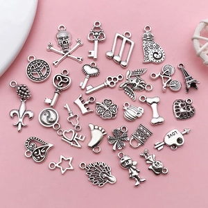 Flat lay of diverse antique silver charms for DIY jewelry including hearts and keys