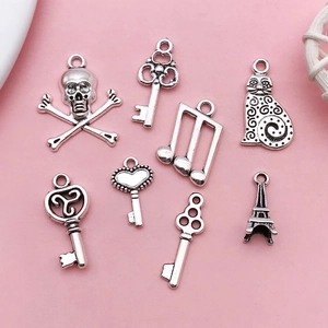 Assorted vintage silver alloy charms for DIY necklaces and bracelets on pink background