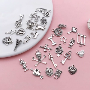 Macro view of assorted vintage silver charms for DIY jewelry making on white ceramic plate