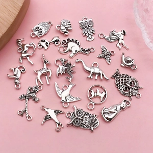 Vue à plat de breloques d'animaux en argent vintage pour bijoux sur fond rose