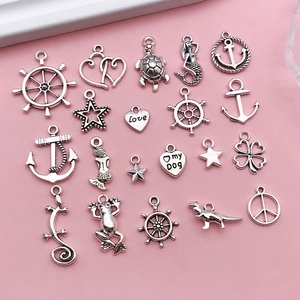 Flat lay of vintage silver alloy nautical charms featuring anchor and mermaid shapes
