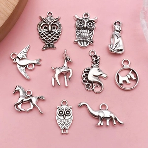Vue détaillée de pendentifs animaux argentés tels que hiboux et chats sur fond rose