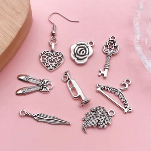 Set of 8 antique silver DIY charms with heart, leaf and rose shapes on pink background