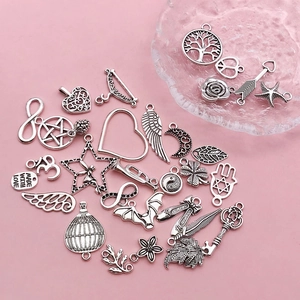 Flat lay of antique silver charms with tree and heart motifs for DIY jewelry making