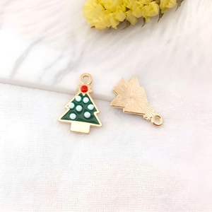 Dettaglio del ciondolo a forma di albero di Natale in smalto verde con bordi dorati e gancio