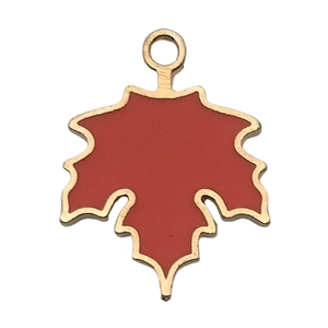 Macro shot of maple leaf charm with red enamel finish and golden metal edges for DIY jewelry