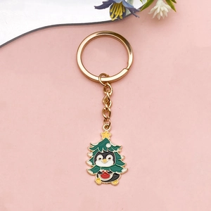 Christmas penguin keychain with green tree costume and golden keyring on pink background