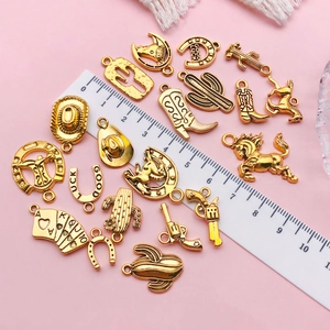 Antique gold western charms set with cowboy hats and cacti on pink background