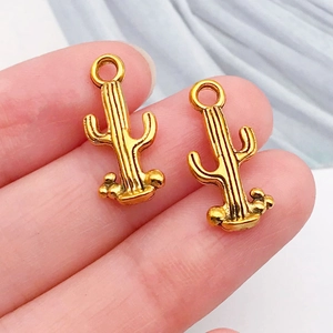 Macro shot of two golden cactus charms with relief texture for DIY jewelry making
