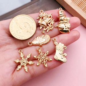 Set de 6 dijes navideños dorados con copo de nieve y muñeco de nieve en comparación de talla
