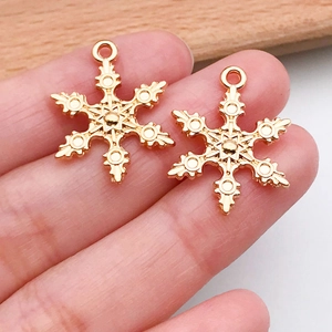 Primer plano de dos colgantes dorados de copos de nieve para joyas artesanales