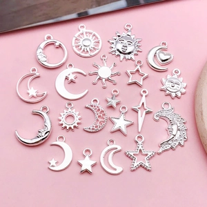 Détail de pendentifs célestes argentés avec soleil lune et étoiles sur fond rose clair
