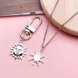 Pendentifs soleil en argent antique avec porte-clés et collier sur support en bois