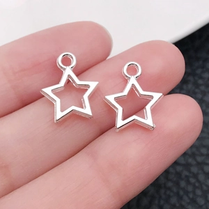 Gros plan de breloques étoiles évidées en argent portées à la main pour bijoux DIY