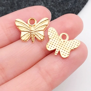 Detailansicht goldener Schmetterlingsanhänger mit filigraner Flügelstruktur auf Fingern