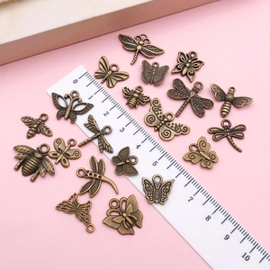 Surtido de dijes de insectos de bronce vintage con mariposas sobre fondo rosa