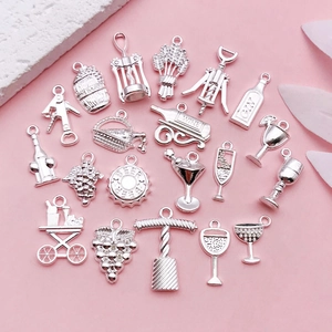 Macro shot of silver alloy wine theme charms for DIY jewelry making on pink backdrop