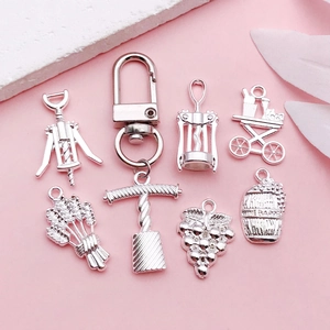 Detailed silver-plated wine themed charms featuring barrels and grape clusters on pink background