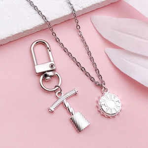 Silver wine opener keychain and beer cap pendant necklace set on soft pink background
