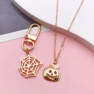 Detail of gold Halloween pumpkin necklace and spider web keychain charm in alloy metal
