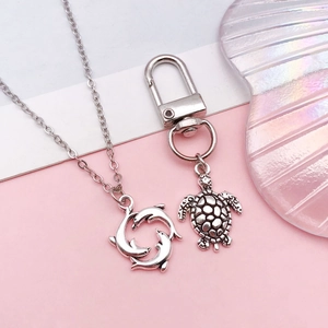 Silver marine charms featuring dolphins and sea turtle pendant on soft pastel background