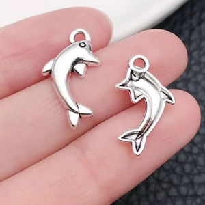 Detailed close-up of a pair of dolphin pendants in vintage silver showing front and back
