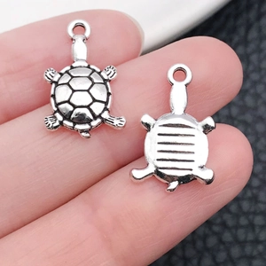 Macro detail of two tibetan silver sea turtle pendants showing front and back textures