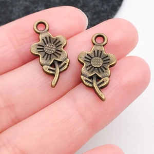Macro detail of antique bronze flower pendants on finger showing size and texture