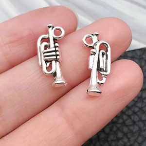 Detailed macro of two miniature silver horn pendants with intricate musical instrument textures