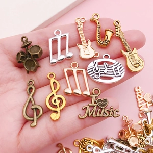 Pendentifs instruments de musique assortis en or et argent tenus en main sur fond rose clair