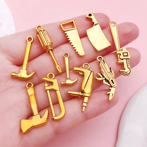 Pendentifs outils en alliage doré pour bricolage DIY, montrés à la main pour échelle