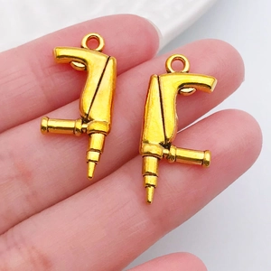 Mini pendentifs perceuse dorés pour bijoux DIY présentés sur le doigt pour l'échelle