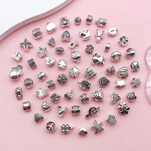 Mixed silver alloy charms for bracelets featuring heart and star symbols on pink background