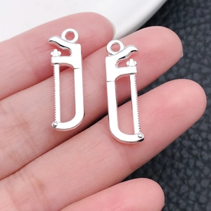 Vue macro de mini pendentifs en forme de scie en alliage argenté pour bijoux DIY