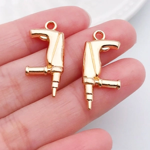 Detail von handgehaltenen Mini-Werkzeuganhängern aus Goldlegierung für DIY-Schmuck