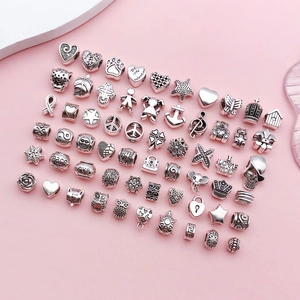 Close-up of mixed silver alloy beads featuring hearts, owls, and turtles for DIY jewelry making