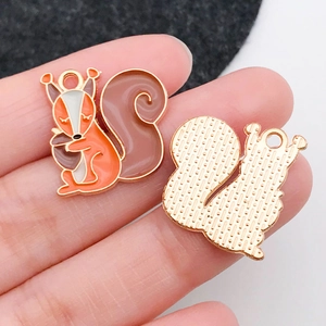 Detailed macro of squirrel enamel charms for DIY jewelry showing front and back textures