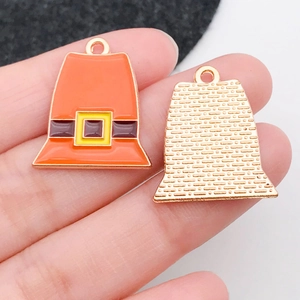 Macro view of pilgrim hat charms showing orange enamel front and textured gold back