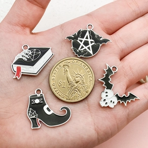 Gothic Halloween charms set with bat and spellbook next to a dollar coin for size comparison