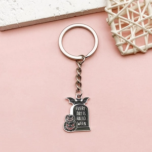 Halloween keychain with bat tombstone and pumpkin pendant on pink background