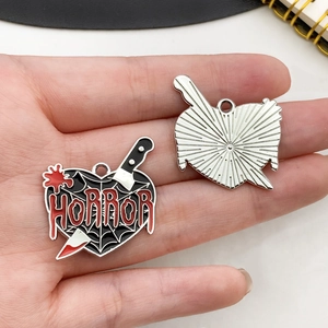 Detail view of heart-shaped horror pendant with dagger and spider web enamel