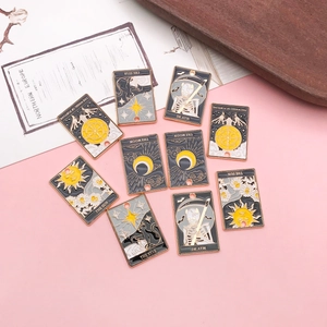 Nahaufnahme bunter Emaille-Tarot-Anhänger mit Sonnen- und Mondmotiven auf Rosa