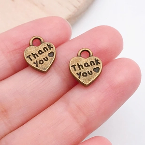 Macro shot of vintage bronze heart-shaped DIY charm pendants with Thank You engraving