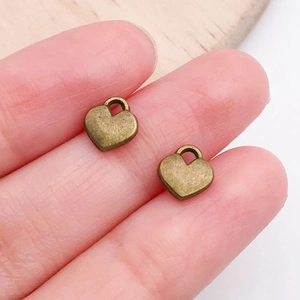 Macro view of two small antique bronze heart-shaped metal charms for jewelry making