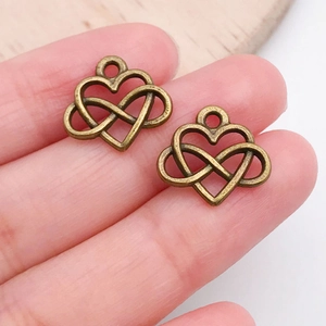 Close-up of antique bronze heart and infinity charms held in hand for DIY jewelry making