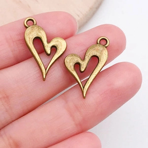 Close-up of bronze heart-shaped hollow charms held by hand to show actual size