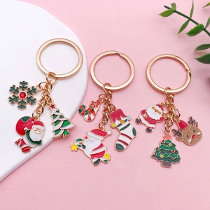Christmas keychain set with Santa, reindeer, and tree enamel pendants on pink background