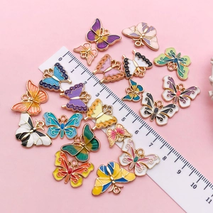 Enamel butterfly charms in various colors on pink background with measuring ruler