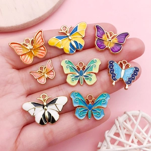 Detailed view of colorful enamel butterfly charms held in hand to show the actual product size